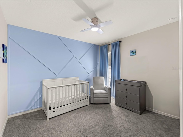 carpeted bedroom featuring a crib, ceiling fan, and baseboards