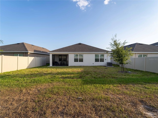 rear view of house with a fenced backyard, stucco siding, a sunroom, central AC unit, and a yard