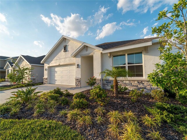 single story home featuring an attached garage, stucco siding, stone siding, and concrete driveway