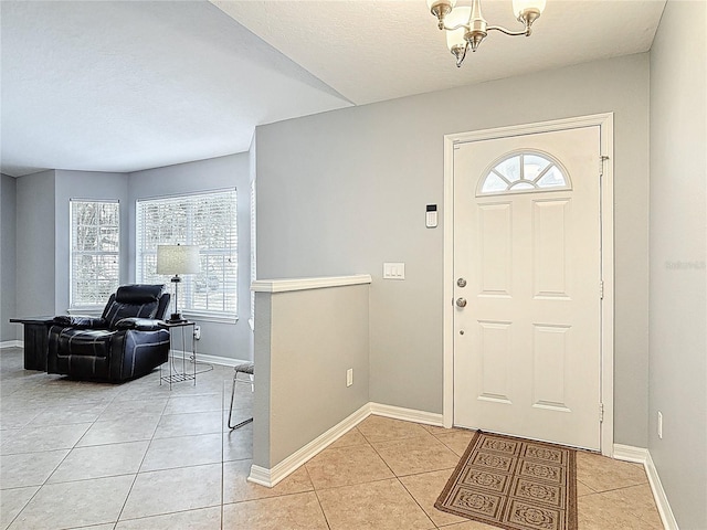 entryway with baseboards, light tile patterned floors, and an inviting chandelier