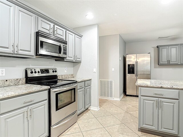 kitchen featuring light tile patterned flooring, gray cabinets, stainless steel appliances, baseboards, and visible vents