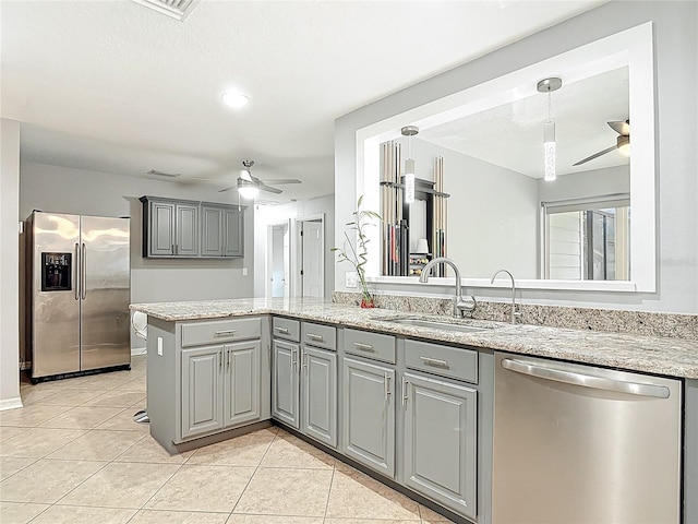 kitchen with light tile patterned flooring, ceiling fan, appliances with stainless steel finishes, a sink, and gray cabinetry