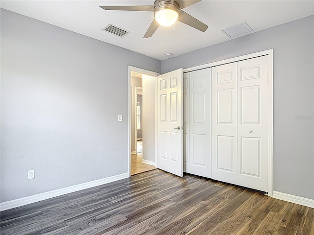 unfurnished bedroom with visible vents, dark wood finished floors, baseboards, and a closet