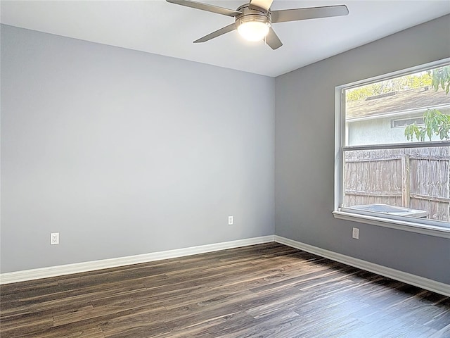 spare room featuring baseboards, a ceiling fan, and dark wood-style flooring