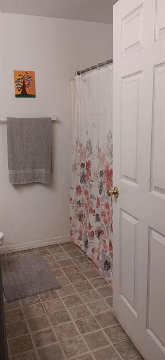 bathroom featuring toilet and curtained shower