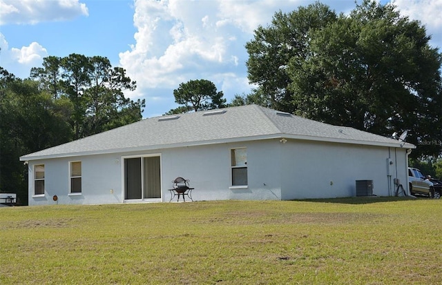 back of property with a lawn, central AC unit, and stucco siding