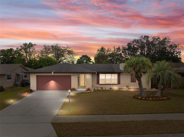 ranch-style house featuring an attached garage, concrete driveway, and a front yard