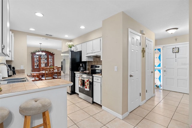 kitchen featuring a sink, stainless steel appliances, tile countertops, light tile patterned floors, and under cabinet range hood
