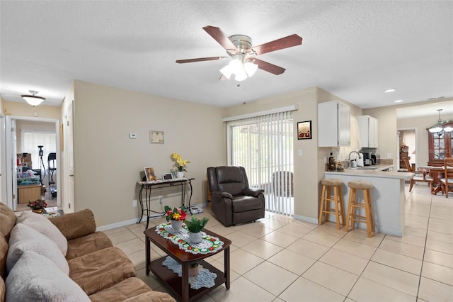 living room with light tile patterned floors, ceiling fan, a wealth of natural light, and a textured ceiling