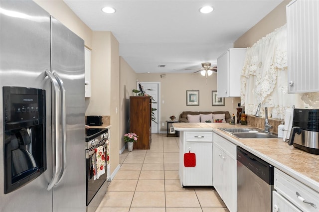 kitchen with a peninsula, white cabinetry, a sink, appliances with stainless steel finishes, and light tile patterned floors