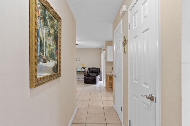 hallway featuring baseboards and light tile patterned flooring