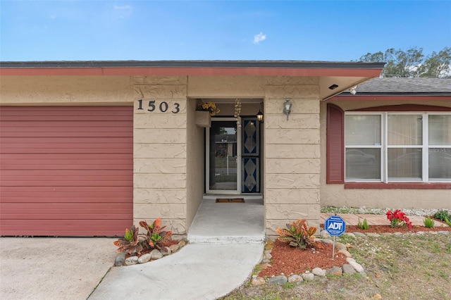 entrance to property featuring a garage and stucco siding