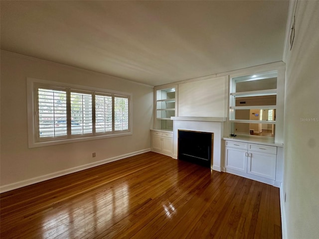unfurnished living room featuring baseboards, built in features, dark wood-type flooring, and a fireplace