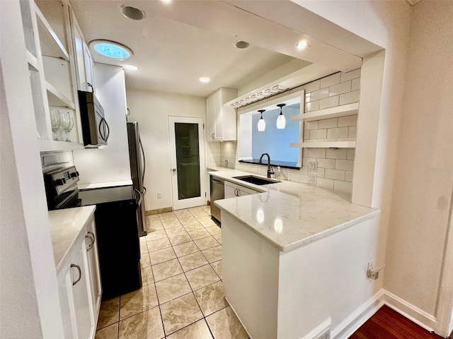 kitchen with appliances with stainless steel finishes, a sink, white cabinetry, baseboards, and decorative backsplash