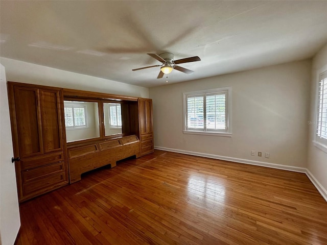 unfurnished bedroom with baseboards, multiple windows, and hardwood / wood-style floors