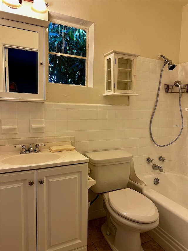 bathroom featuring vanity, wainscoting, toilet, tile walls, and washtub / shower combination