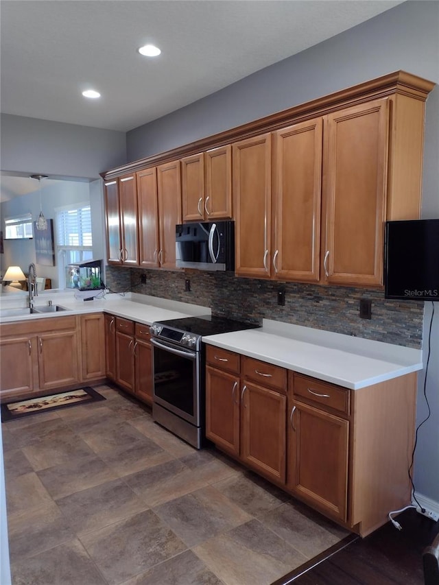 kitchen with brown cabinetry, a sink, stainless steel electric range, and tasteful backsplash