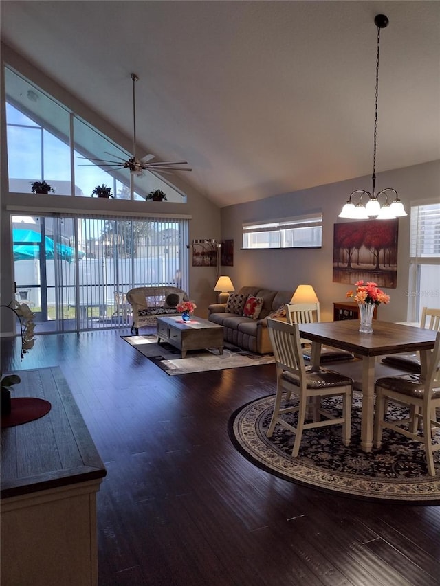 dining space with vaulted ceiling, a wealth of natural light, wood finished floors, and ceiling fan with notable chandelier