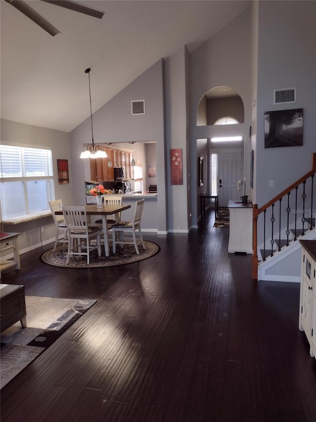 dining room featuring high vaulted ceiling, baseboards, a notable chandelier, and visible vents