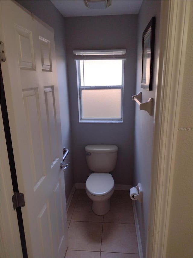 bathroom featuring baseboards, tile patterned floors, visible vents, and toilet