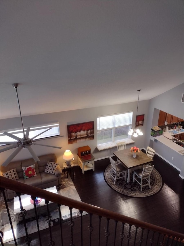 living area featuring baseboards, ceiling fan with notable chandelier, and wood finished floors