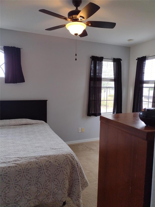 carpeted bedroom featuring baseboards and ceiling fan