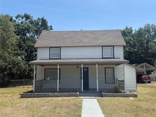 view of front facade featuring a shingled roof, a front lawn, fence, and covered porch