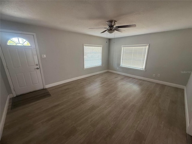 entryway with baseboards, a ceiling fan, a textured ceiling, and dark wood-style flooring