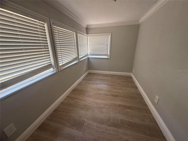 spare room featuring baseboards, a textured ceiling, ornamental molding, and wood finished floors
