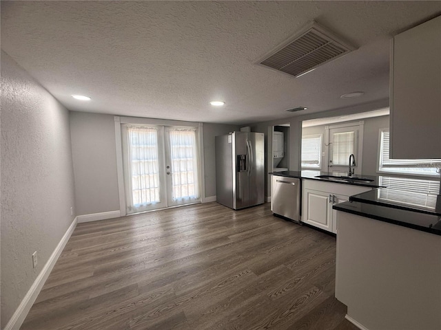 kitchen featuring visible vents, dark countertops, a sink, dark wood finished floors, and appliances with stainless steel finishes