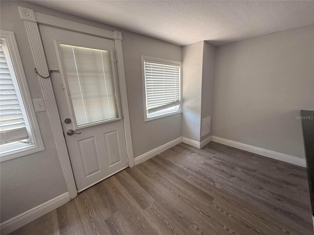 entryway with baseboards, a textured ceiling, and wood finished floors