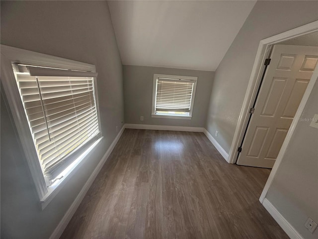 empty room featuring baseboards, vaulted ceiling, and dark wood finished floors