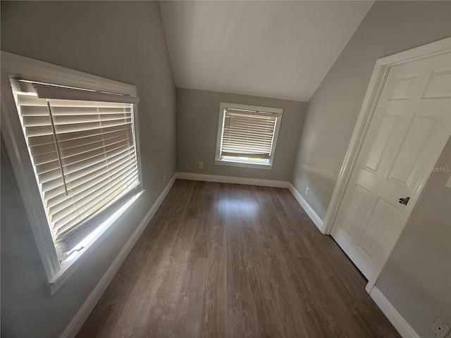 empty room with baseboards, vaulted ceiling, and dark wood-style flooring