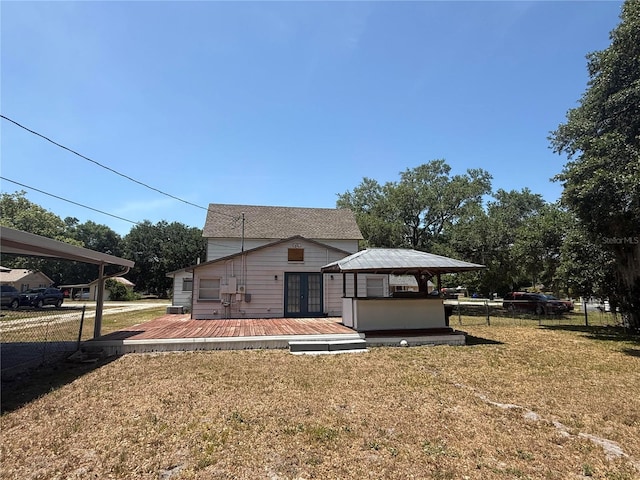 rear view of house featuring fence, a yard, and a deck