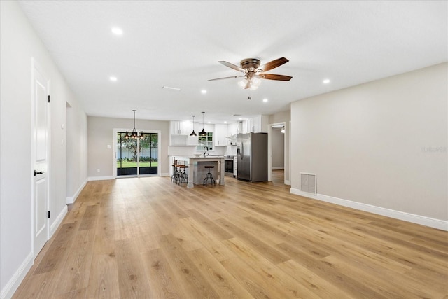 5162 Tellson Pl, Orlando, FL 32812 - unfurnished living room with visible vents, recessed lighting, light wood finished floors, and ceiling fan with notable chandelier