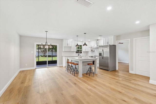 5162 Tellson Pl, Orlando, FL 32812 - kitchen featuring white cabinets, stainless steel fridge, a kitchen bar, a kitchen island, and visible vents