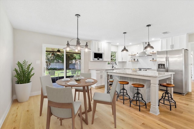 5162 Tellson Pl, Orlando, FL 32812 - kitchen with exhaust hood, backsplash, visible vents, light wood finished floors, and stainless steel fridge