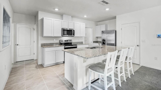 kitchen with visible vents, a kitchen bar, light stone counters, a sink, and stainless steel appliances