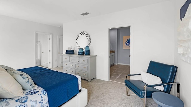 bedroom with light tile patterned flooring, light carpet, baseboards, ensuite bathroom, and visible vents