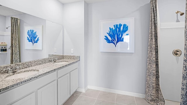 full bathroom featuring double vanity, baseboards, a sink, and tile patterned flooring