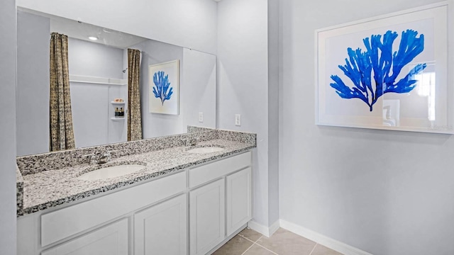 full bathroom with double vanity, baseboards, a sink, and tile patterned flooring