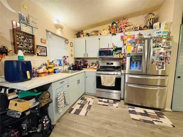 116 Lincoln Ave Unit 116-118, Cape Canaveral, FL 32920 - kitchen with appliances with stainless steel finishes, light wood-style flooring, a textured ceiling, light countertops, and backsplash