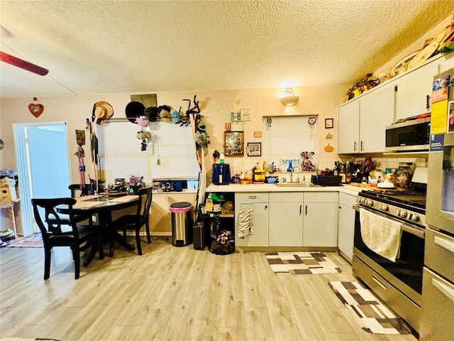 116 Lincoln Ave Unit 116-118, Cape Canaveral, FL 32920 - kitchen with stainless steel appliances, a textured ceiling, light wood finished floors, light countertops, and white cabinetry