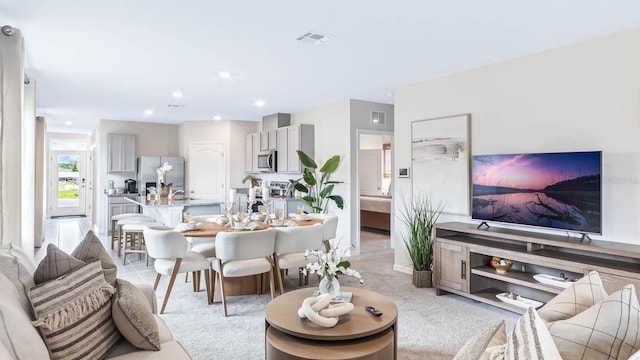 living area featuring recessed lighting, light colored carpet, and visible vents