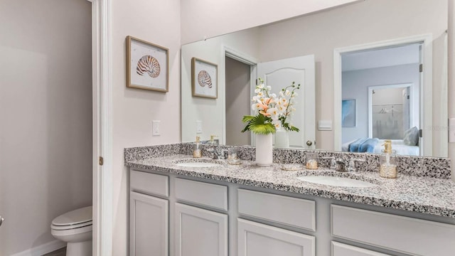 ensuite bathroom with a sink, toilet, double vanity, and connected bathroom