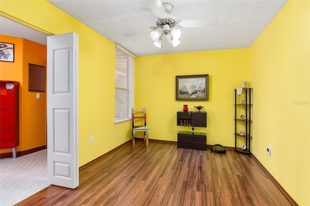 sitting room featuring baseboards, a textured ceiling, ceiling fan, and wood finished floors
