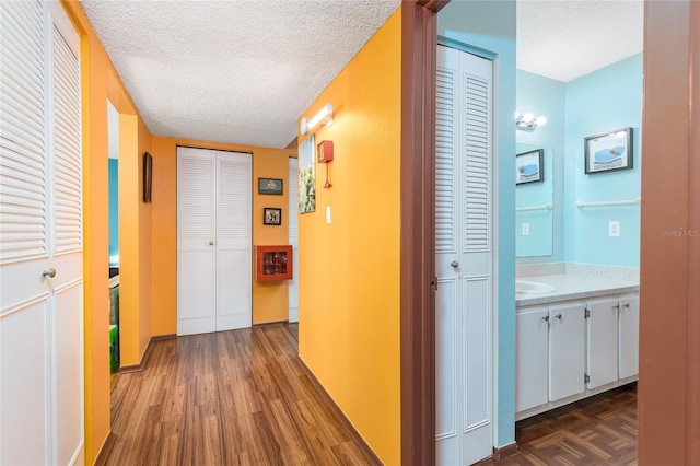 hallway with dark wood-style floors and a textured ceiling
