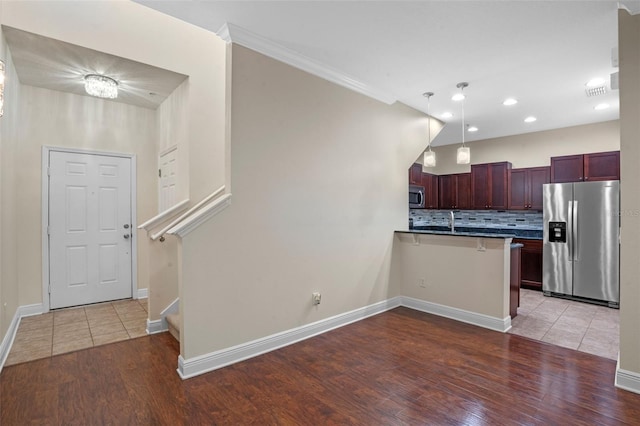 8031 Enchantment Dr Unit Ge, Windermere, FL 34786 - kitchen with light wood finished floors, a peninsula, reddish brown cabinets, stainless steel appliances, and tasteful backsplash