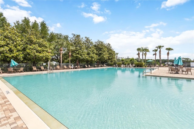 community pool with fence and a patio area
