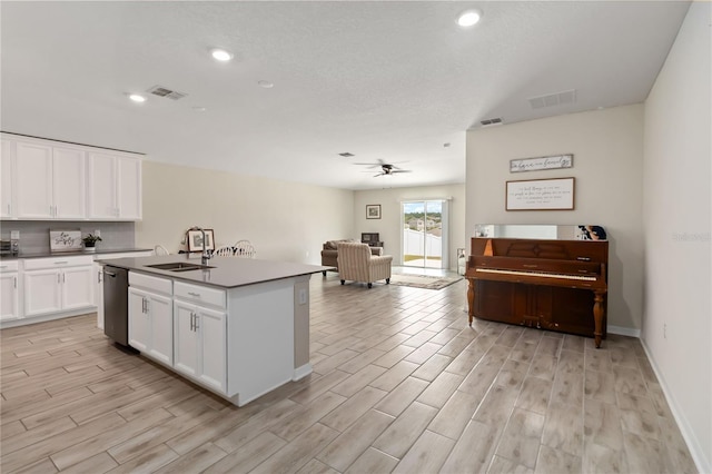 5347 Travertine St, Mount Dora, FL 32757 - kitchen featuring stainless steel dishwasher, a sink, open floor plan, light wood-style floors, and white cabinets